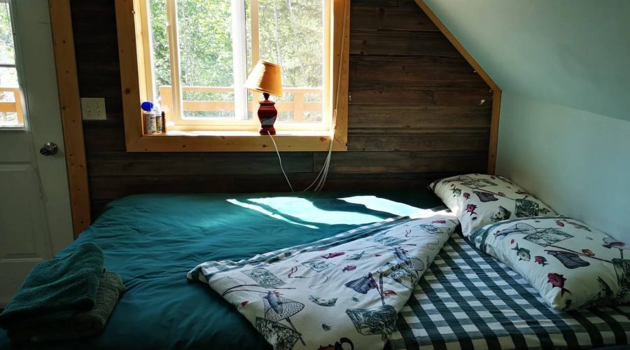Interior view of the Marten Cabin at Yellow Dog Lodge. The cabin has a queen size bed and 3 singles and is equipped with a wood stove for heat. It is cozy and feature down filled comforters and is more private than the lodge rooms.